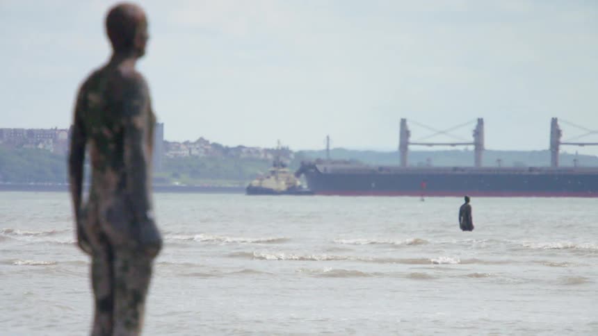 A person covered with mud is standing by the water