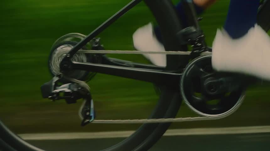 Close up of a bicycles tire and pedals as a cyclist rides on a road during daytime
