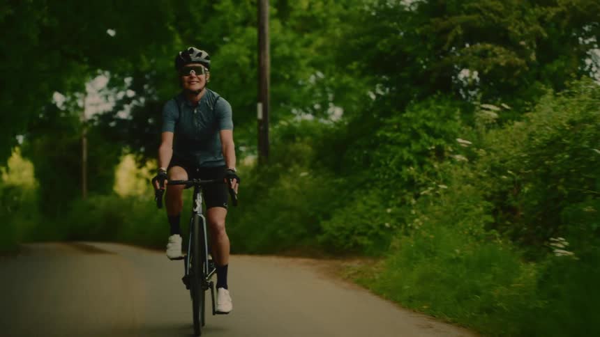 Female cyclist riding on a green trail with a happy expression