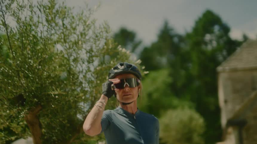 Woman in cycling attire putting on sunglasses