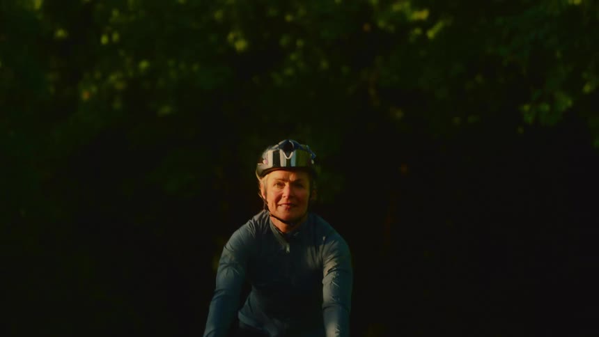 The woman is riding her bike on the trail through the forest