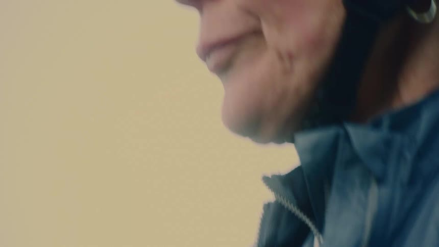 The face of a woman wearing a blue jacket and a protective helmet on her head