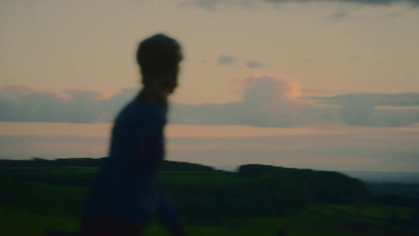 A woman on a bicycle looking at the natural landscape and a sky with clouds