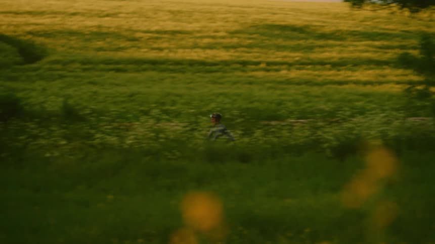 A woman rides her bike past the fields
