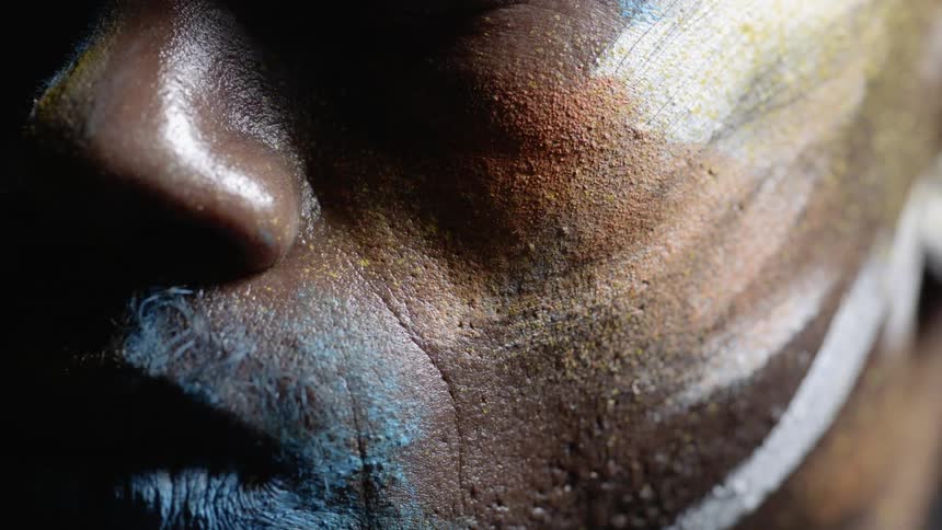 Light shines on a painted man's face