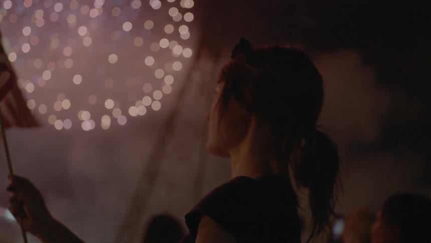 Woman waves american flag during fireworks show