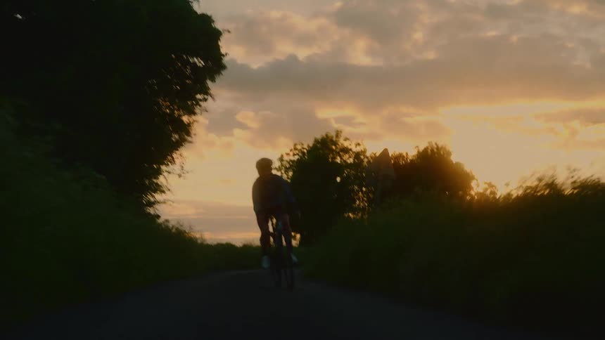 A woman riding a bicycle under the sunset