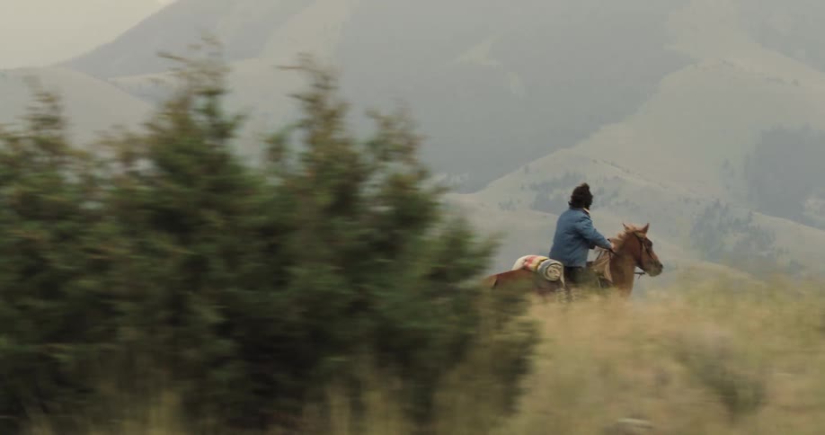 Man and woman riding horses in a mountain area during the day