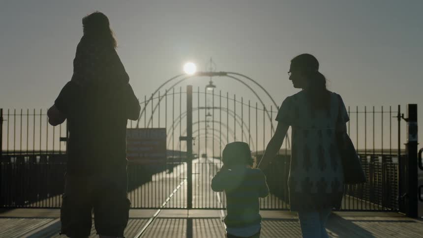 A family with young children walks on a pier
