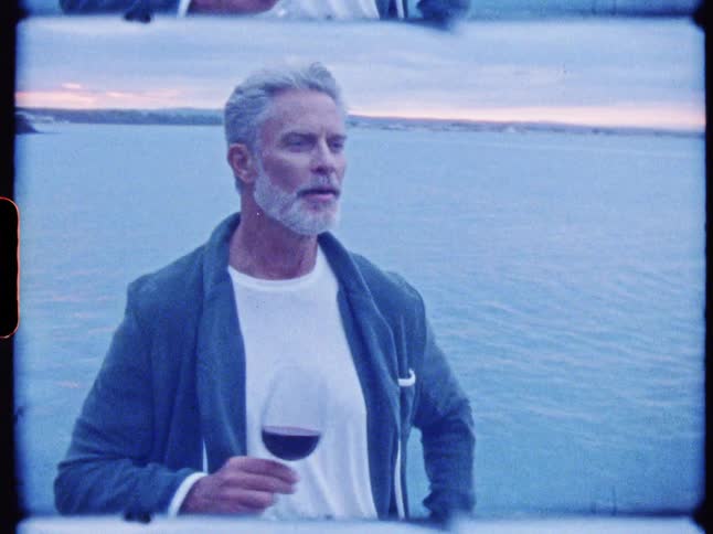 Man at the seaside holding a glass of wine