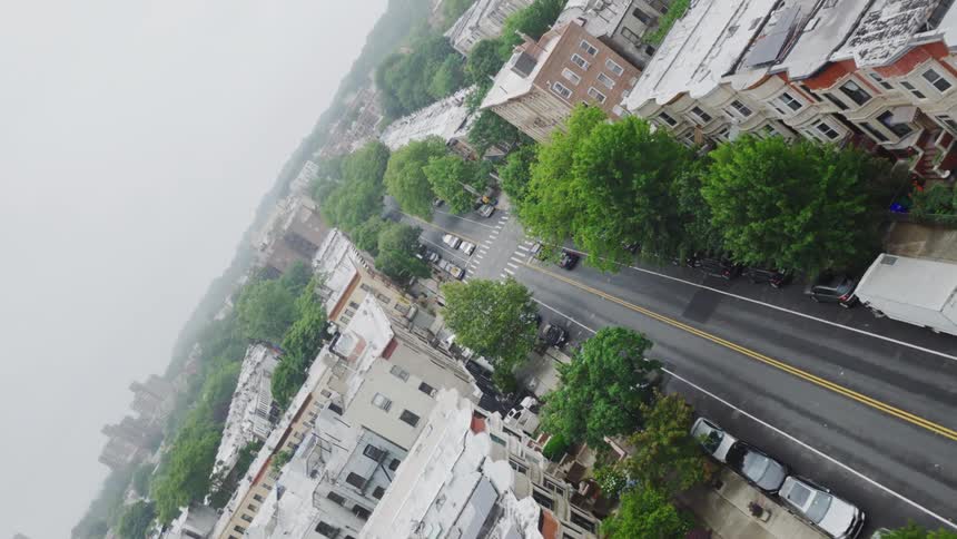 Vehicles pass through an intersection in a residential neighborhood on a foggy day