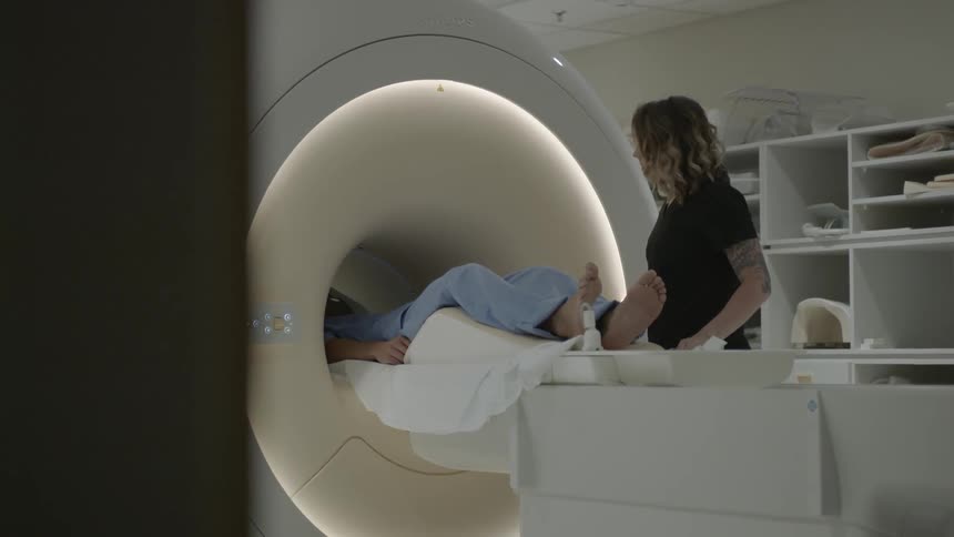 A woman slides a patient into an mri machine