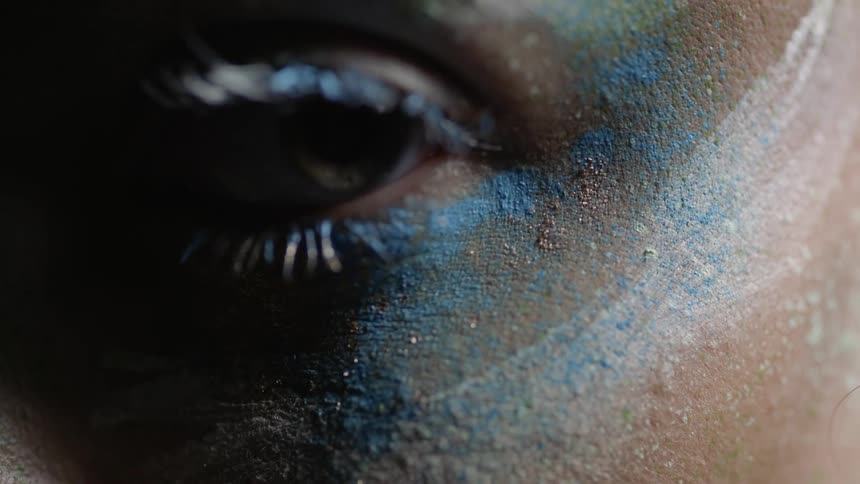 Colorful powder surrounds an eye as it opens