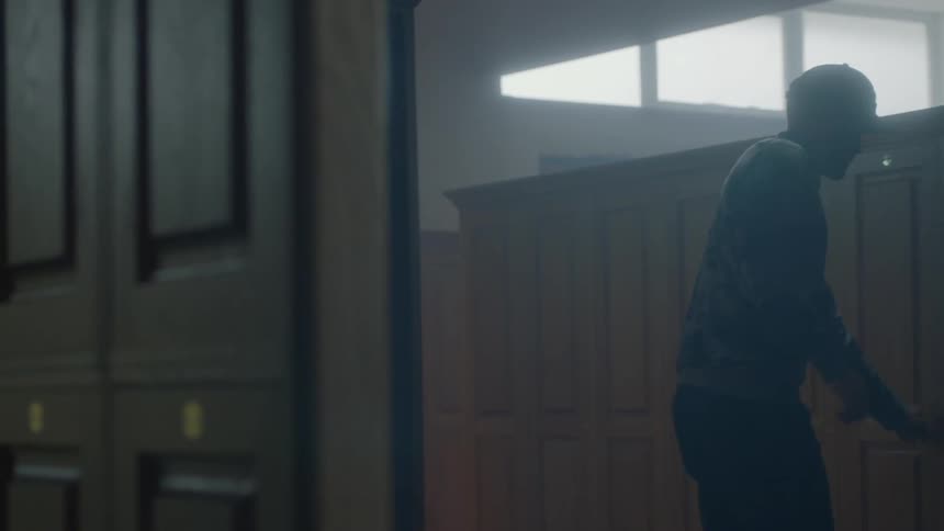 A man puts on a hat and closes a cupboard door