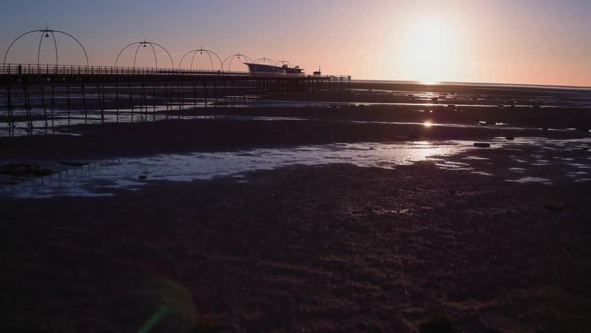 A pier goes out into the beach at dawn