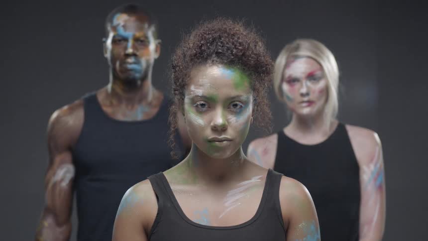 Two women and a man with painted faces and arms