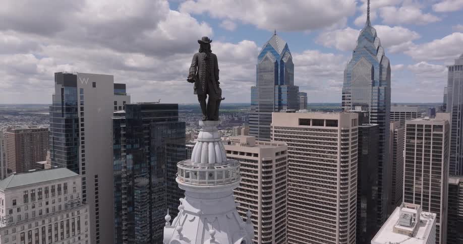 The statue of William Penn atop Philadelphia city hall is seen at midday surrounded by a series of highrise and skyscraper buildings in the city