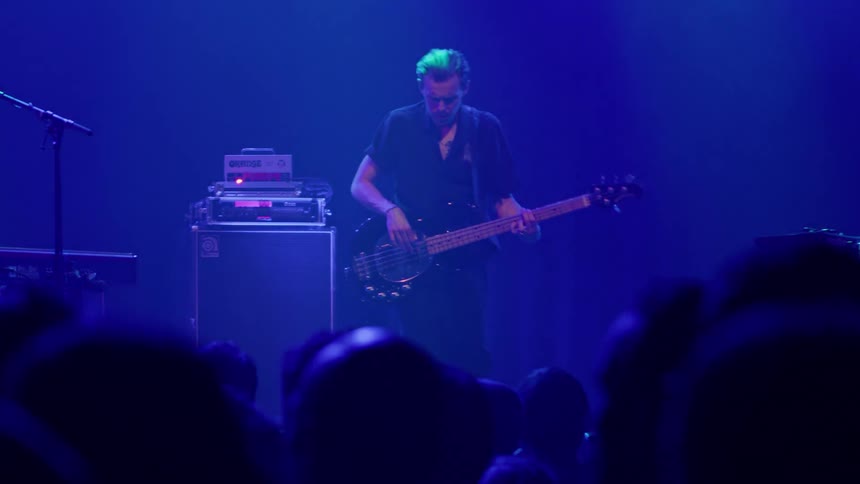 A man playing bass on stage during a show for the audience
