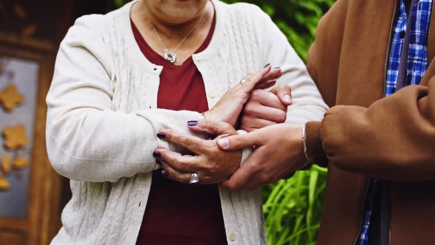 A man helping an elderly woman down the steps of her house