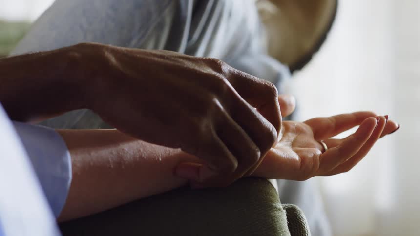 Two people share a tender moment holding hands closely while sitting together