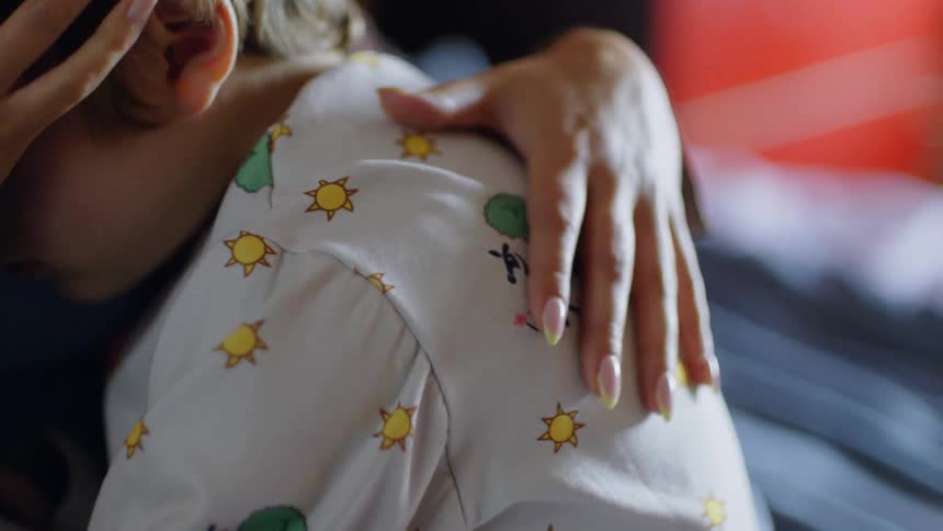 A child sleeping while leaning on a woman who is gently caressing him