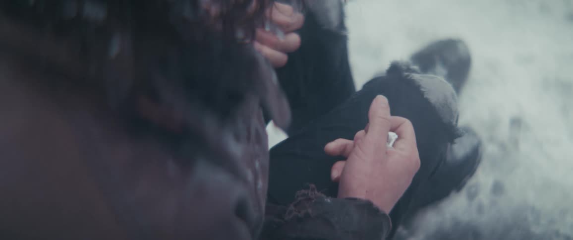A person clutches their hands while freezing in the snow
