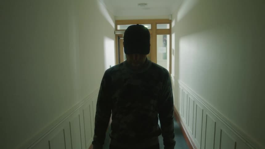 A man is walking through a narrow corridor in a building