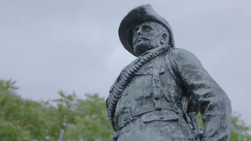 A statue of a man fills the cloudy sky