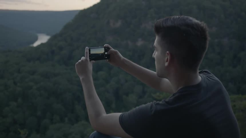 Man sits at the edge of a cliff and takes a picture