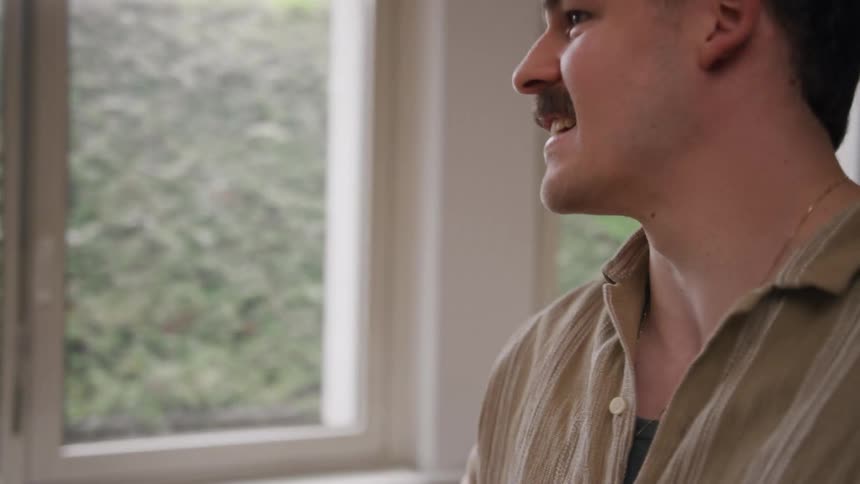 A man walks up to a coworker in the office and gives him flowers