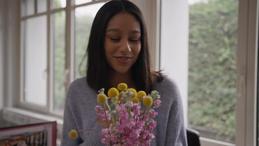 A young lady receives a flower with a smile on her face from a man while in her cubicle at midday