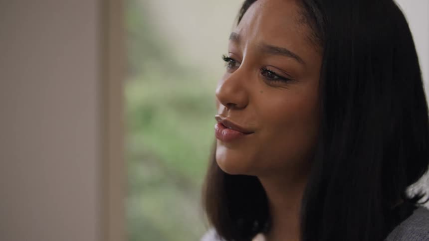 A woman is smiling as she has a conversation with a friend
