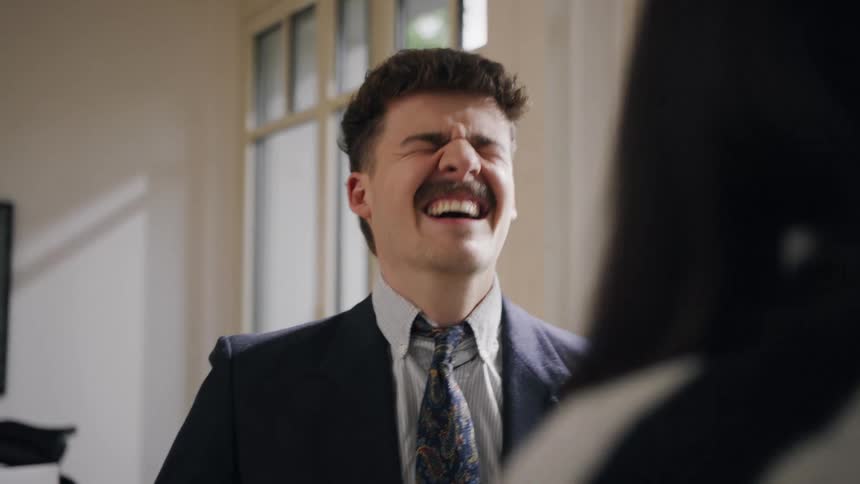 Man in suit and tie talking smiling to another person