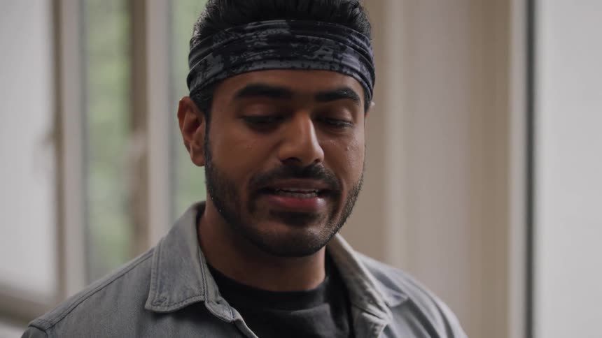 Man with a headband in an indoor space talking