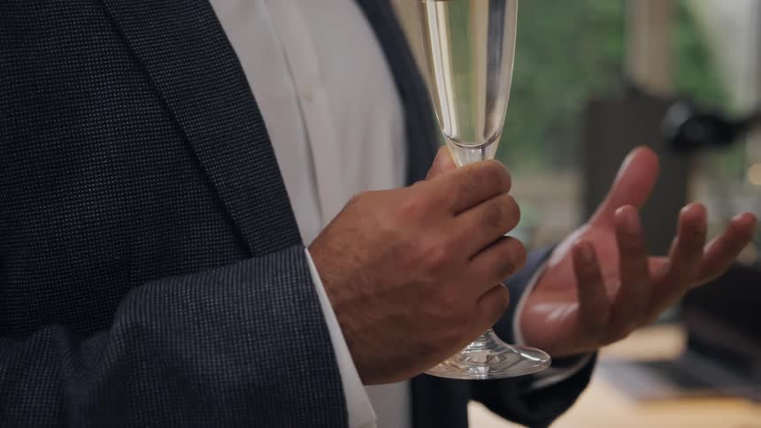A man is talking while holding an alcoholic beverage