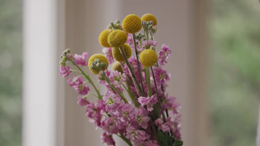 A woman giving a bouquet of flowers to another woman who receives the bouquet and smells the flowers
