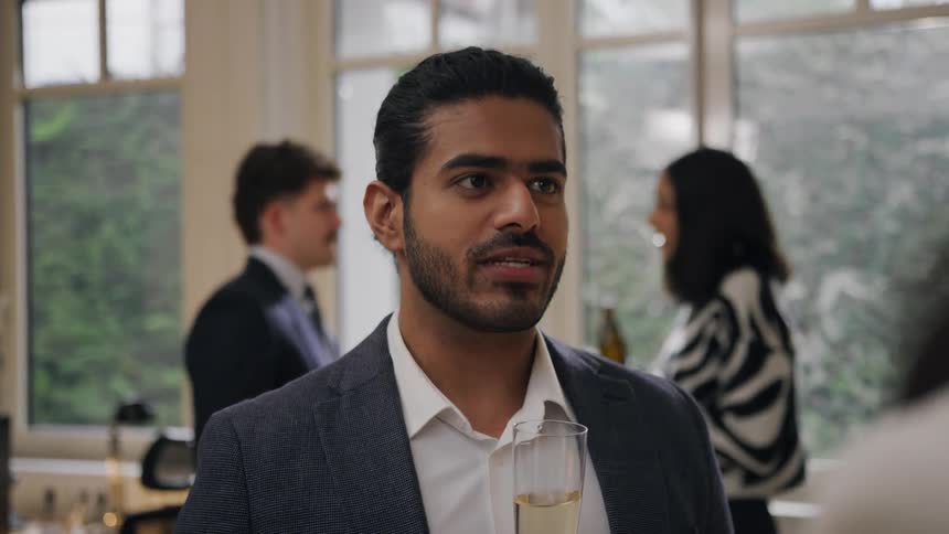 Man smiling during a lively conversation at a social gathering indoors