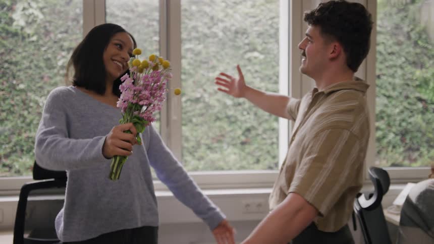 A man gives a woman flowers and gives her a hug