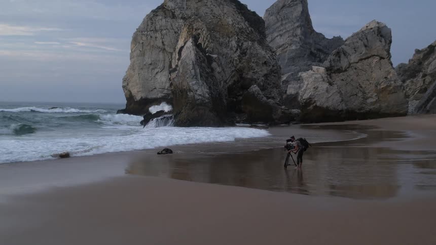 A person is photographing the coastline with heavy waves