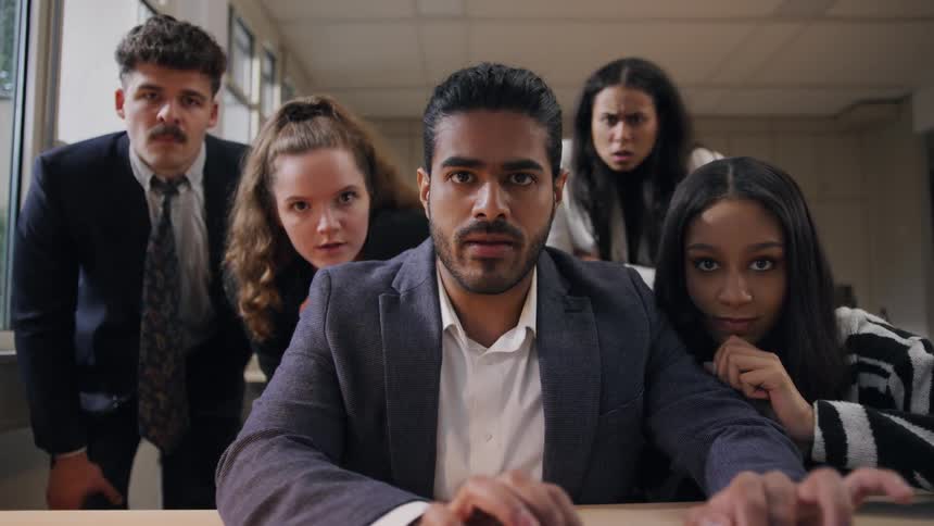 Office workers watch intently then celebrate when their coworker succeeds in his computer activities