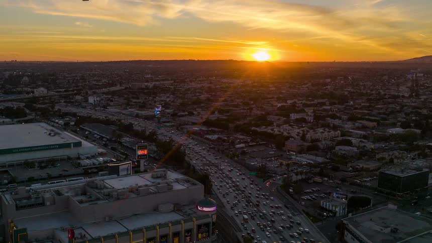 Aerial view of a busy city highway at sunset with golden light bathing the urban Los Angeles landscape