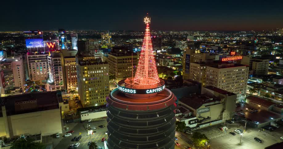 A tower on top the Capitol Records building stands prominently in the city skyline surrounded by skyscrapers and highrise buildings at night