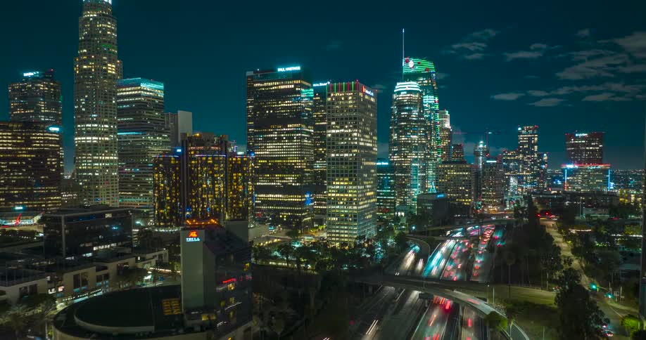 Timelapse of busy nighttime traffic flowing beneath a glowing downtown  Los Angeles  skyline