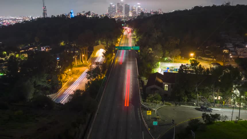 Highway with illuminated vehicle traffic at night reveals Los Angeles on the horizon