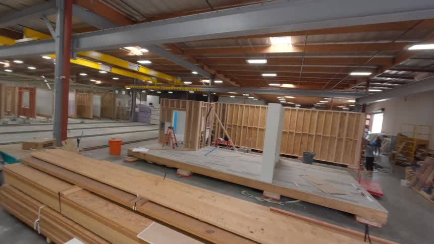 An FPV drone flying inside a warehouse with worker's building structures