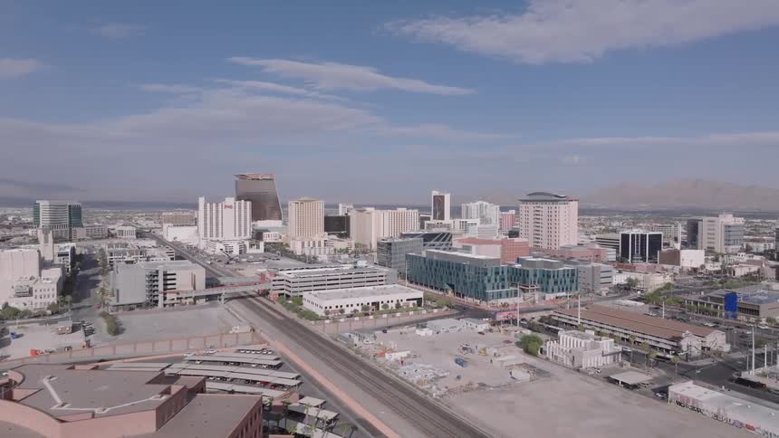 A skyline view of downtown Las Vegas shows a series of buildings and structures under the midday sun
