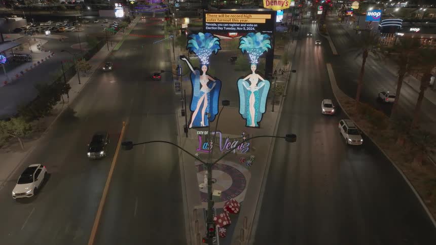 A freeway in Las Vegas at night features numerous billboard ads as a series of cars drive by