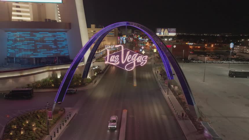 A series of cars pass under the Las Vegas Boulevard gateway arches at night