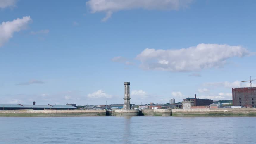 A waterway flows along a boardwalk with a concrete tower