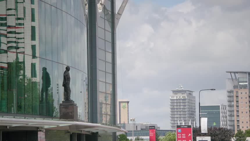 Statue of a standing man outside glass building